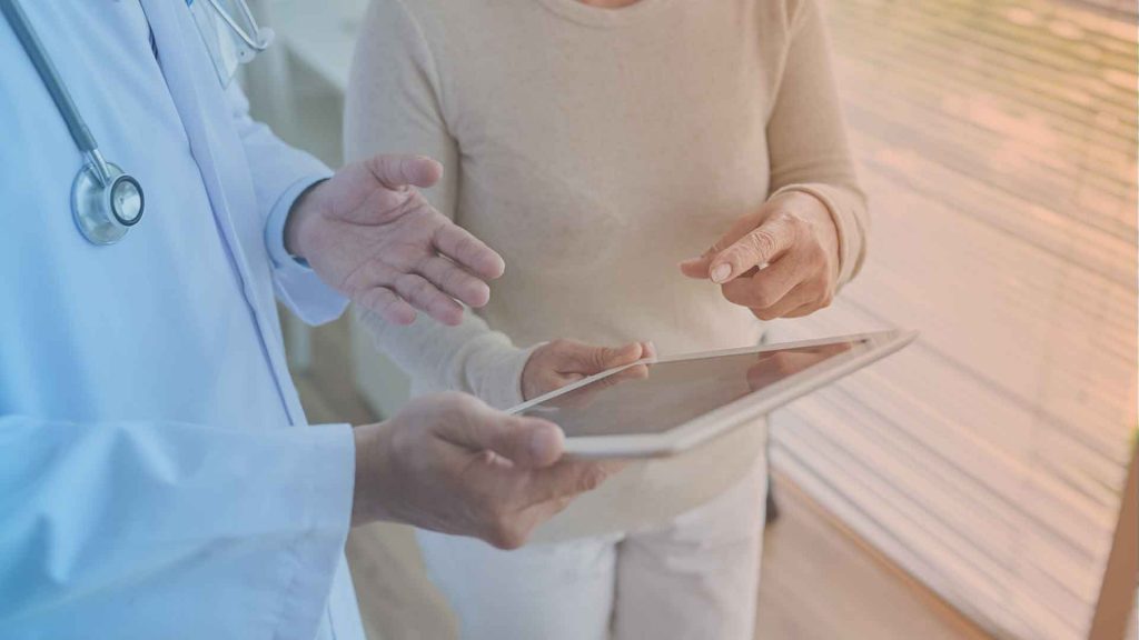 Ärztin erläutert PatientIn die digitale Datenerfassung zu einem Fragebogen