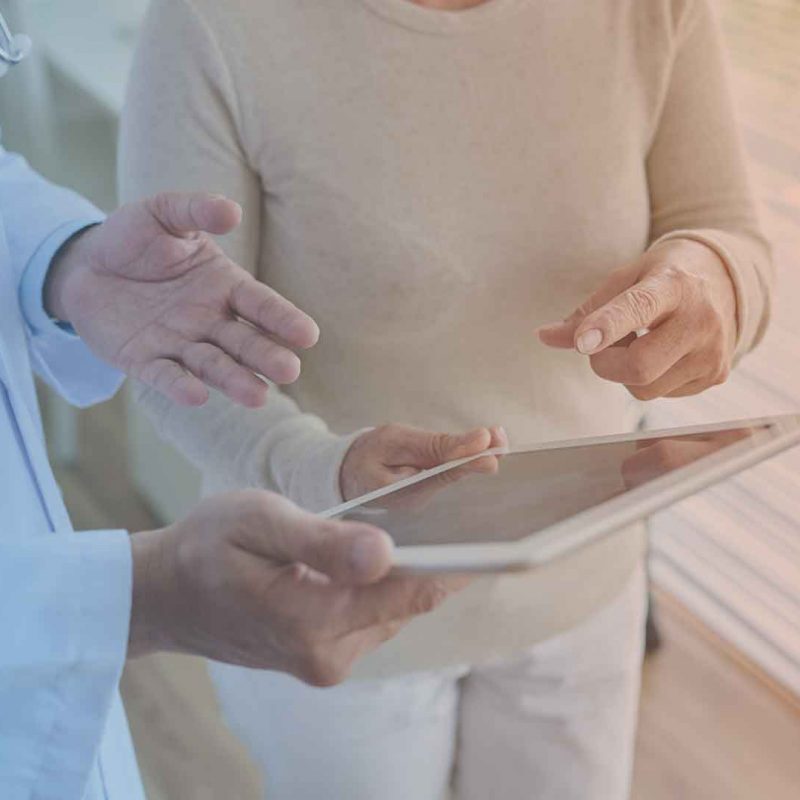 Ärztin erläutert PatientIn die digitale Datenerfassung zu einem Fragebogen