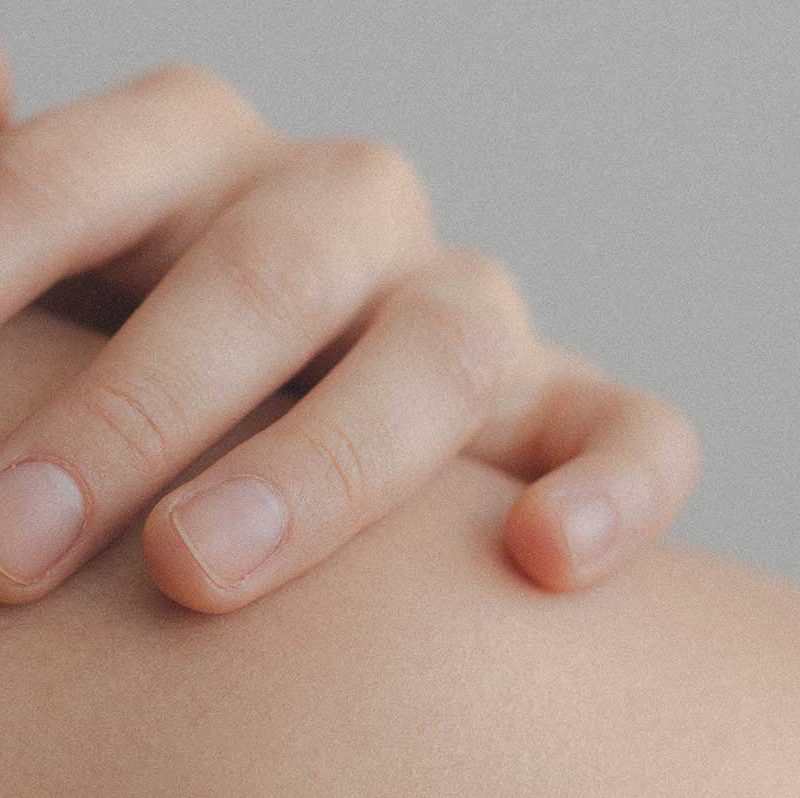 Hand berührt Haut am Nacken
