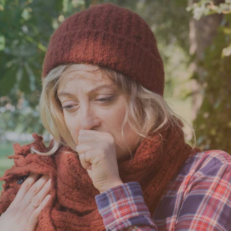 Frau hustet aufgrund einer Erkältung