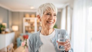 Ältere Frau mit einem Glas Wasser.