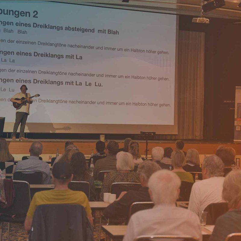 Markus Baltensperger führt mit seiner Gitarre eine Gesangsübung an