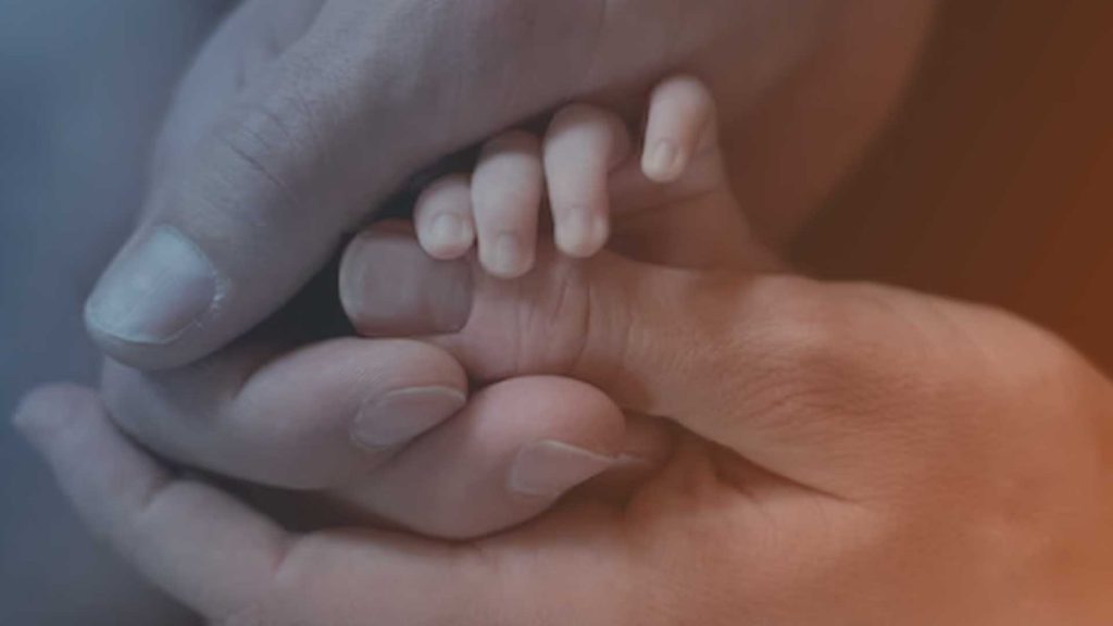 Babyhände in den Händen der Eltern.