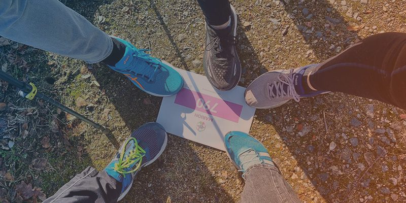 Fünf Beine die auf einem Teilnehmerschild des Rare-Diseases-Run von 2026 stehen