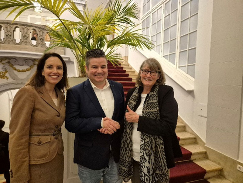 Drei Personen von denen sich zwei die Hände schütteln.