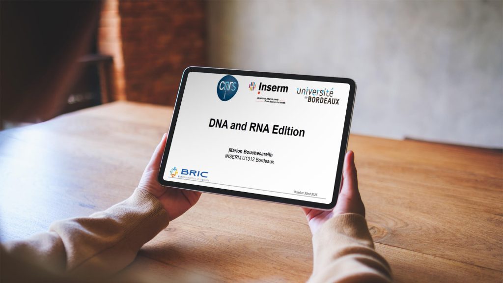 A person holds a tablet displaying a presentation titled "DNA and RNA Edition" by Marina Bouscharain, with logos of CNRS, Inserm, Université de Bordeaux, and BRIC visible.